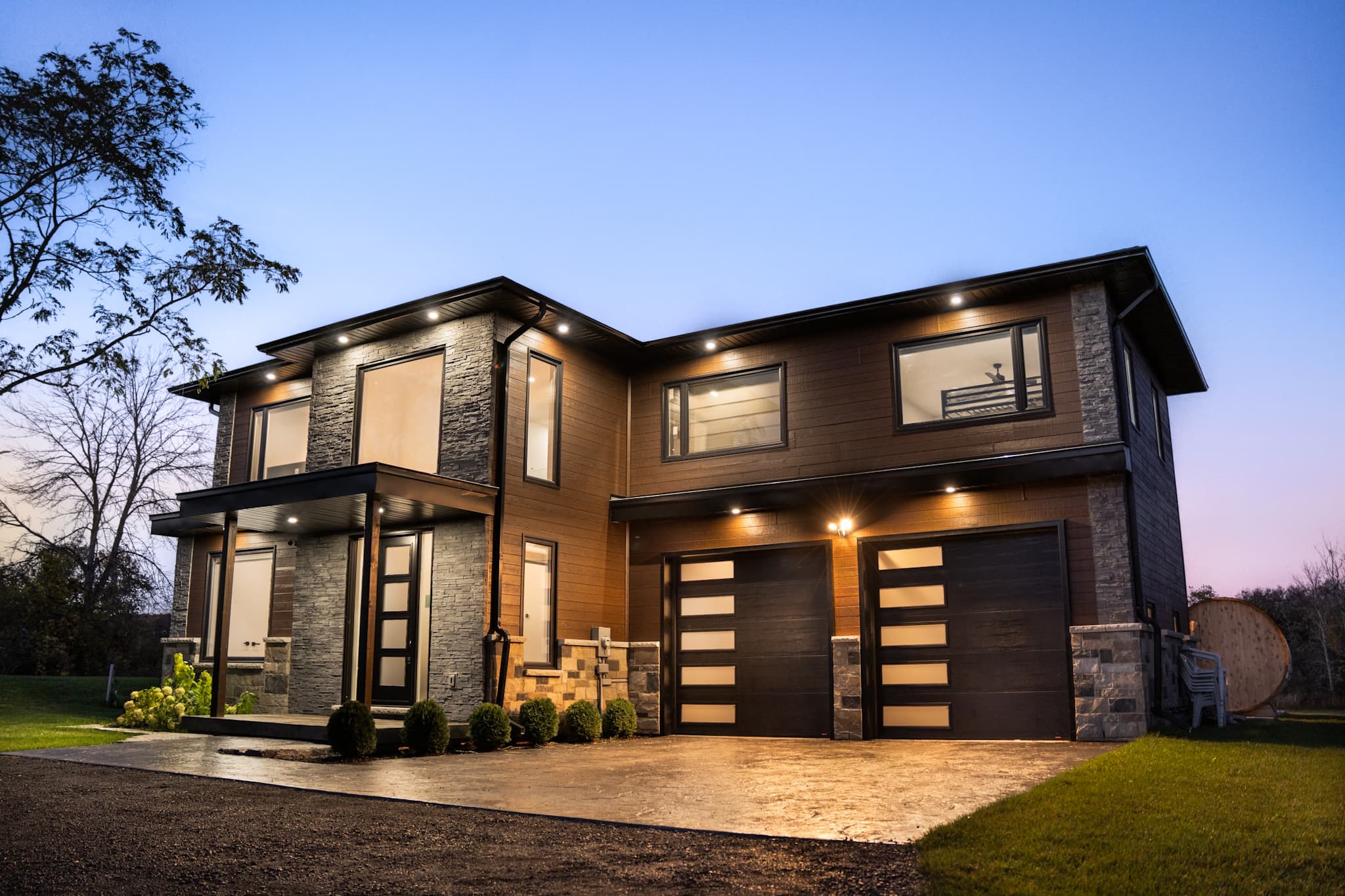 Abdul’s House, a modern riverfront home at dusk with a fire pit and Muskoka chairs